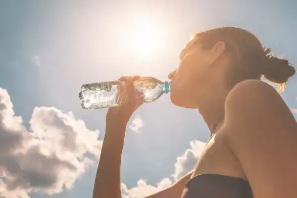 Hydration: The Secret Ingredient for a Toned Stomach and Enhanced Fitness 3 Image of woman drinking water to hydrate Hayes after run.