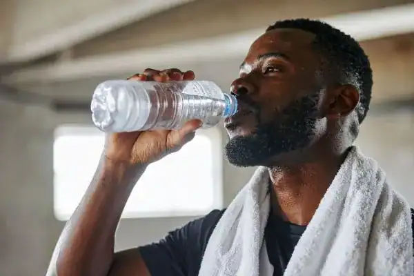 Hydration: The Secret Ingredient for a Toned Stomach and Enhanced Fitness 1 Image of man drinking water to improve hydration Hayes after work out.